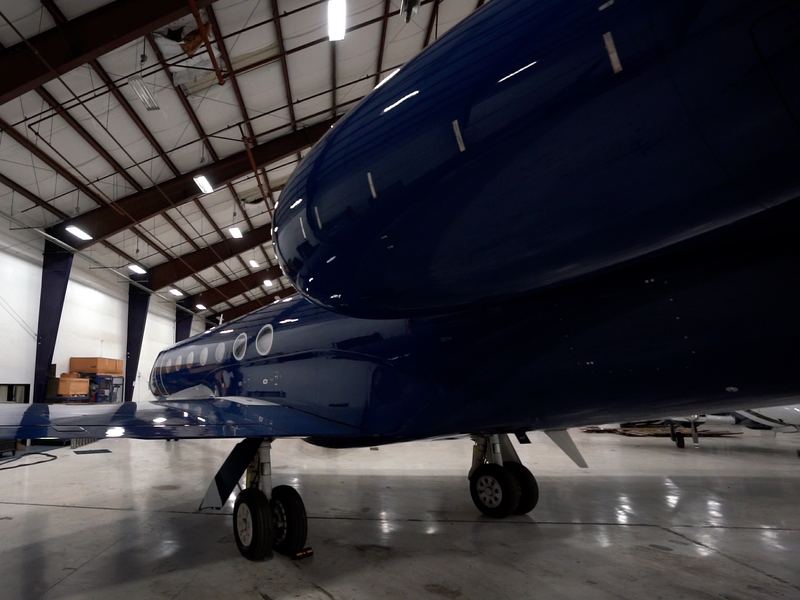 Navy blue business jet in a hangar, light reflecting off its glossy fuselage.
